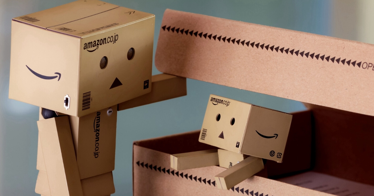  Two cardboard Amazon boxes with faces drawn on them, the larger one opening a smaller one, representing the search query 'Personalised content marketing examples'.